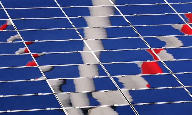 Das Spiegelbild eines Windrads auf Solarmodulen  | Foto: Karl-Josef Hildenbrand (dpa)