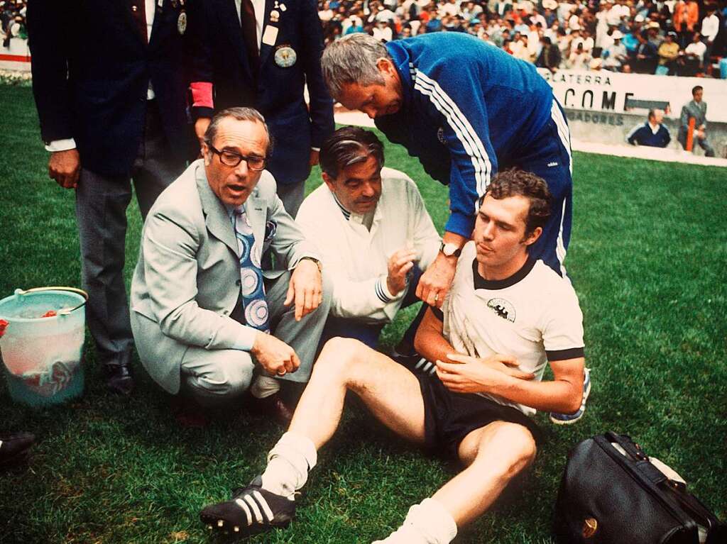 16.06.1970, Mexiko: Franz Beckenbauer wird im Halbfinalspiel der Fuball-WM in Mexiko Deutschland - Italien am 17.6.1970 vom deutschen Mannschaftsarzt Professor Schoberth (l.) und Masseur Erich Deuser (M.) eine Schulterbandage angelegt. Beckenbauer hatte sich zum Ende der regulren Spielzeit eine Verletzung an der Schulter zugezogen und mit dem Verband die zweimal 15 Minuten der Verlngerung durchgestanden. Deutschland verlor das Spiel im Aztekenstadion durch ein Tor von Rivera in der 111. Minute mit 3:4.