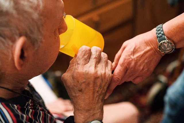 Eine ambulante Pflegerin hilft einem alten Mann bei der Tabletteneinnahme.  | Foto: Jana Bauch (dpa)