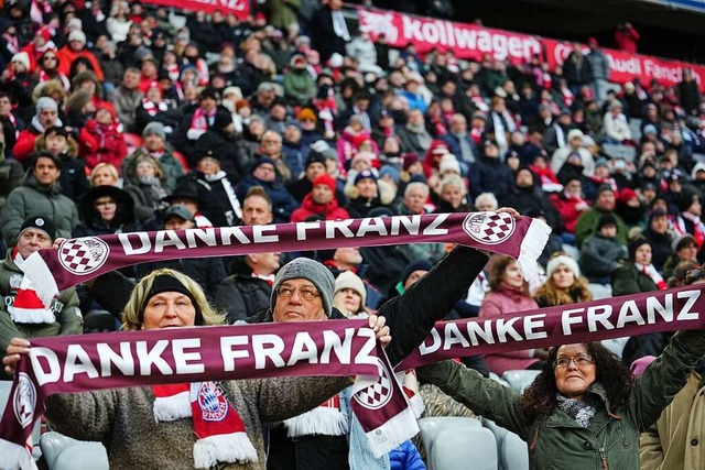 Teilnehmer der Trauerfeier fr Franz B...en Schals zu seinen Ehren in die Hhe.  | Foto: Kay Nietfeld (dpa)