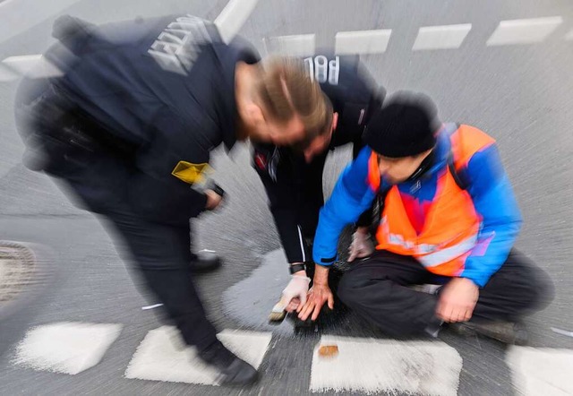 Polizisten versuchen festgeklebte Hnd...mit Speisel von der Strae abzulsen.  | Foto: Julian Stratenschulte (dpa)
