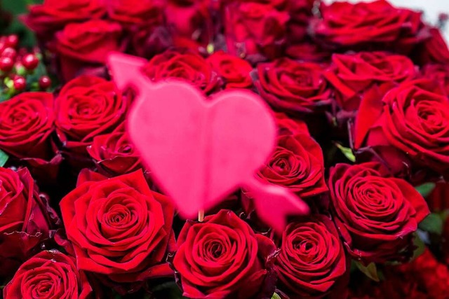 Ein rosa Herz aus Kunststoff steckt in einem Strauss roter Rosen.  | Foto: Peter Kneffel/dpa