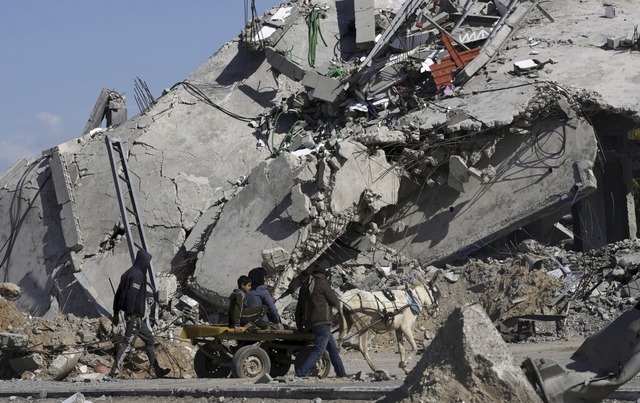 Palstinenser gehen am Donnerstag mit ...ombten Fabrik in Deir al Balah vorbei.  | Foto: Adel Hana (dpa)