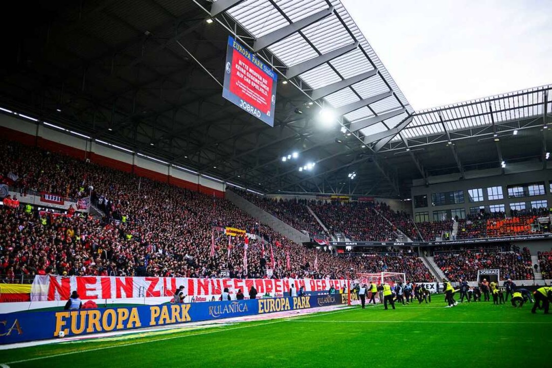 Fans des SC Freiburg protestieren gege...e Ordner auf dem Spielfeld einsammeln.  | Foto: Tom Weller (dpa)