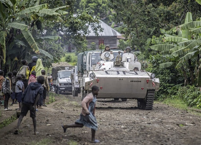 Menschen stehen an einer Strae in Kib...elme in einem militrischen Fahrzeug.   | Foto: Moses Sawasawa (dpa)