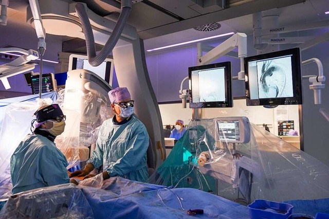 Martin Czerny (rechts) im OP-Saal beim Einsetzen einer Aortenprothese.  | Foto: Britt Schilling