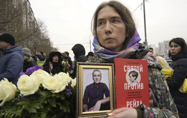 Eine Frau hlt ein Portrt von Alexej ...er gegen das Reich&#8220; in der Hand.  | Foto: Uncredited (dpa)