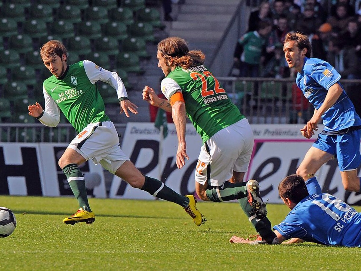 April 2010: Flum liegt am Boden, Schuster schaut hinterher und Bremens Torsten Frings und Aaron Hunt ziehen mit dem Ball davon.