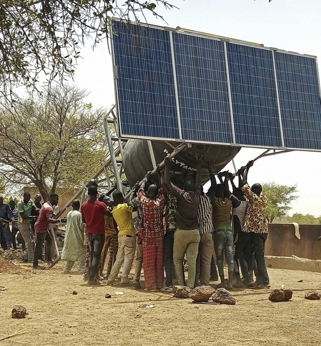 Ein Wasserbehlter mit Solarmodul wird aufgestellt.  | Foto: Georges Bazi