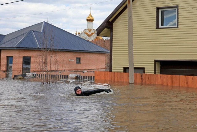 Ein Anwohner schwimmt in der berflute...den berschwemmten Gebieten evakuiert.  | Foto: Uncredited (dpa)