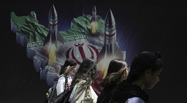 Junge Frauen in Teheran vor einem Propagandaplakat mit Raketen  | Foto: Vahid Salemi (dpa)