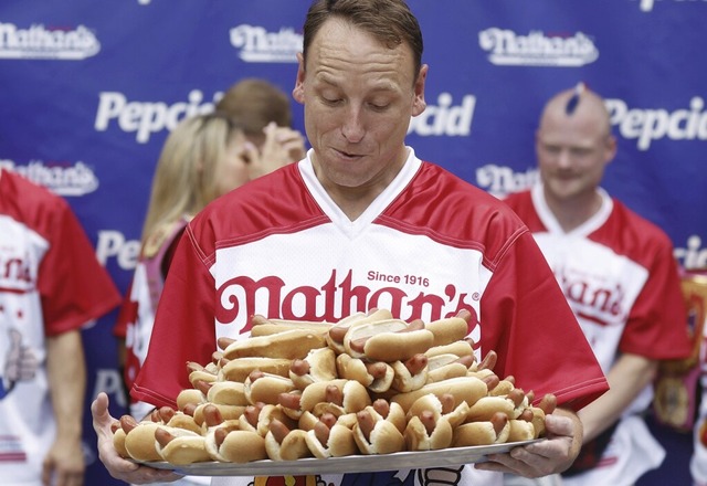 Wettess-Champion Joey Chestnut trgt ein Tablett voller Hotdogs.  | Foto: IMAGO/JOHN ANGELILLO