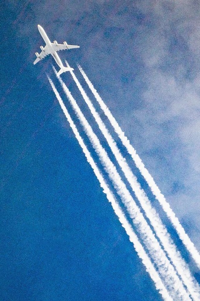 Ein Flugzeug zieht Kondensstreifen hinter sich her.  | Foto: Federico Gambarini (dpa)