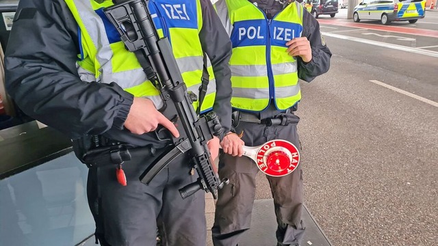 Ein Polizist mit Maschinenpistole sichert das Kontrollteam.  | Foto: Stefan Ammann