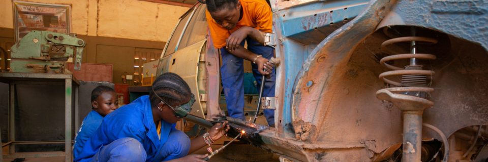 Wie in einer Kfz-Werkstatt in Burkina Faso Frauen an Motorrdern schrauben