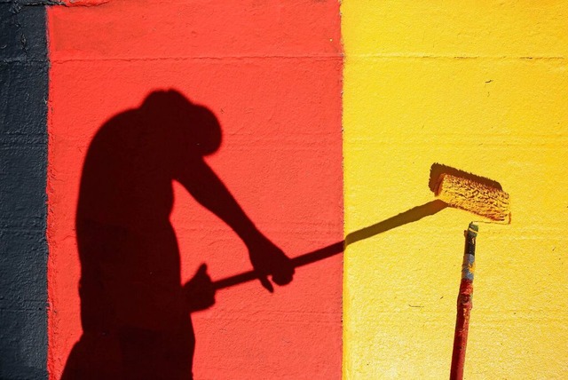 Ein Helfer lackiert  die Kurvensteine ... Farben Schwarz-Rot-Gold (Symbolfoto).  | Foto: Jan Woitas (dpa)