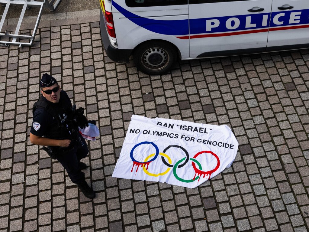 Ein franzsischer Polizist steht neben einem auf dem Boden liegenden Plakat mit der Aufschrift "Ban "Israel No Olympics For Genocide", das whrend eines Laufs mit dem olympischen Feuer durch Huningue konfisziert wurde.