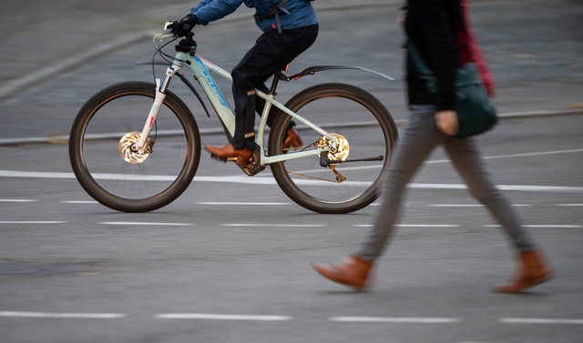 Ein E-Bike-Fahrer berholt im Morgenverkehr eine Fugngerin.  | Foto: Sebastian Gollnow (dpa)