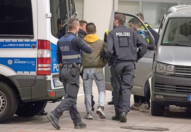 Polizeibeamte  holen Leute, die abgesc...ause ab und bringen sie zum Flughafen.  | Foto: Boris Roessler (dpa)