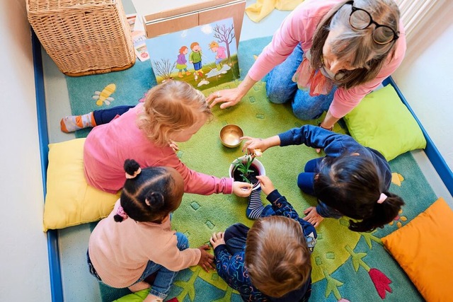 Kinder mit Betreuerin in einer Kindertagessttte   | Foto: Bernd Thissen (dpa)