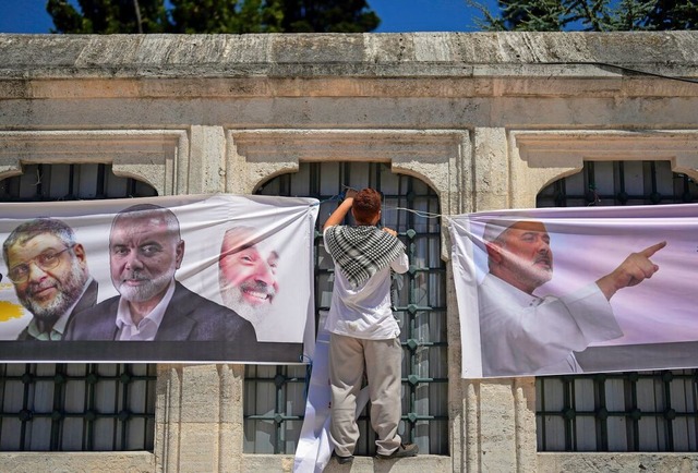 Istanbul: Ein Mann hngt vor der Fatih...es getteten Hamas-Fhrers Hanija auf.  | Foto: Khalil Hamra (dpa)