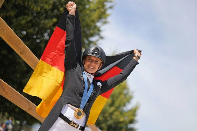 Jessica von Bredow-Werndl zeigt nach der Siegerehrung ihre Goldmedaille.  | Foto: Rolf Vennenbernd (dpa)