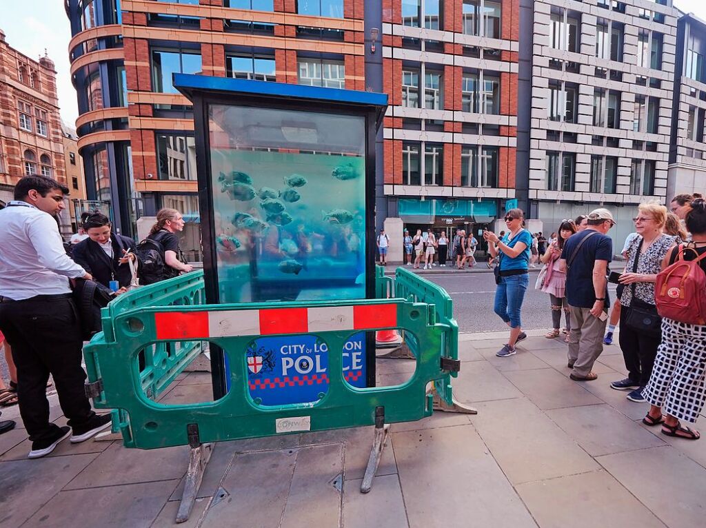 Ein neues Kunstwerk von Banksy mit schwimmenden Fischen, das auf einem Polizeikasten in der Londoner Innenstadt erschienen ist, wird von Arbeitern abgesperrt.