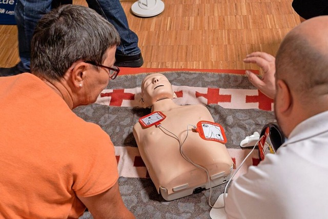 Eine Teilnehmerin des Kurses zur AED-Anwendung inspiziert die Testpuppe.  | Foto: Maximo-Hans Musielik