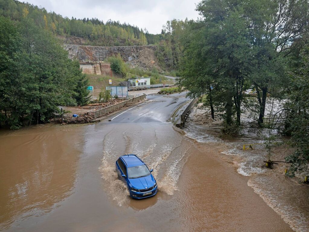 Tschechien, Hanusovice (Hannsdorf): Ein Auto fhrt ber eine berschwemmte Strae.