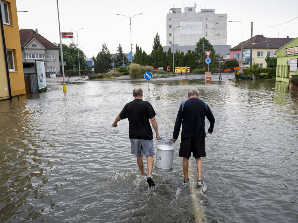 Tschechien, Litovel: Menschen gehen durch eine berflutete Strae.