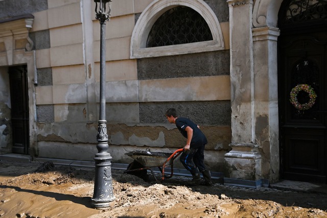 Ein Mann schiebt eine Schubkarre &uuml...erschlammte Stra&szlig;e. (Archivbild)  | Foto: O&#158;ana Jaroslav/CTK/dpa