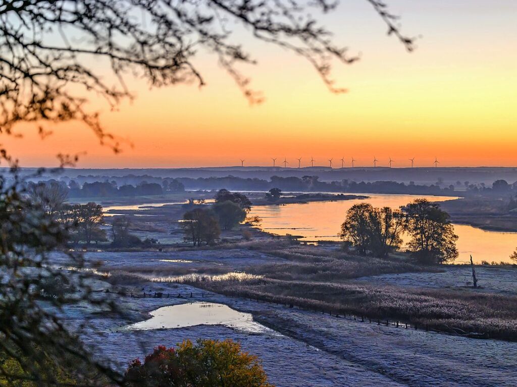 Brandenburg, Lebus: Farbenprchtig leuchtet der Morgenhimmel ber dem Fluss Oder, whrend die Wiesen mit Raureif bedeckt sind.