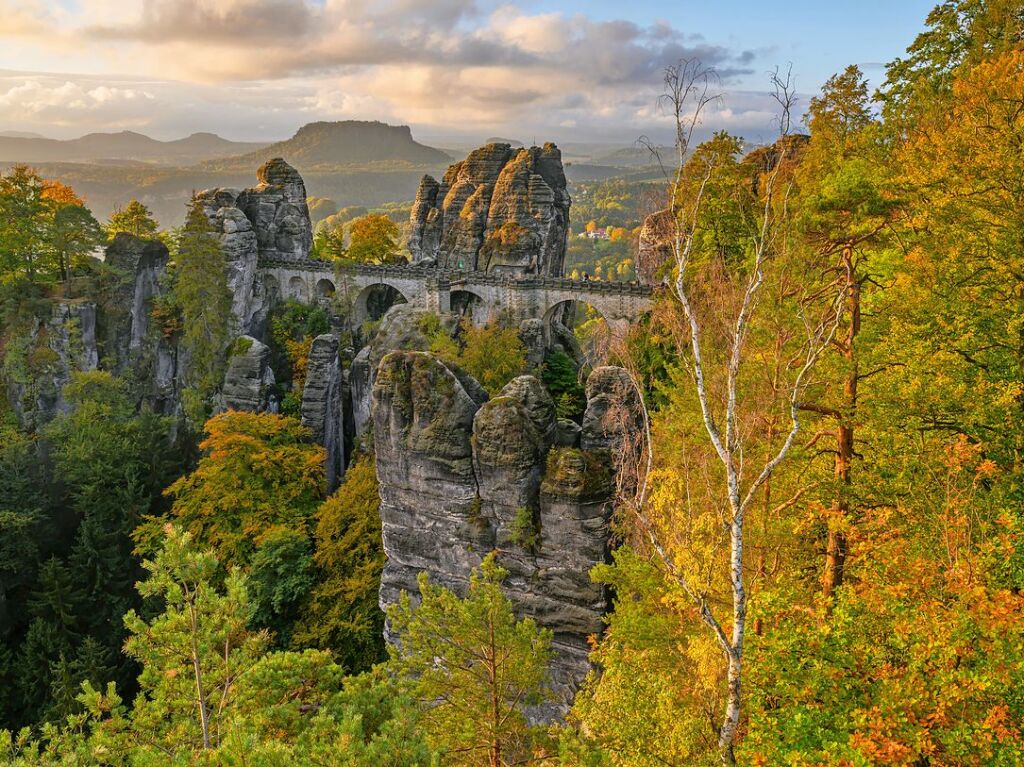 Sachsen, Rathen: Sonnenlicht fllt am Morgen auf die herbstlich gefrbten Bume im Nationalpark Schsische Schweiz nahe der Basteibrcke.