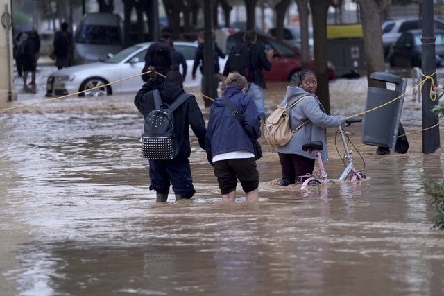 Menschen laufen durch die berfluteten Straen von Valencia.  | Foto: ALberto Saiz (dpa)