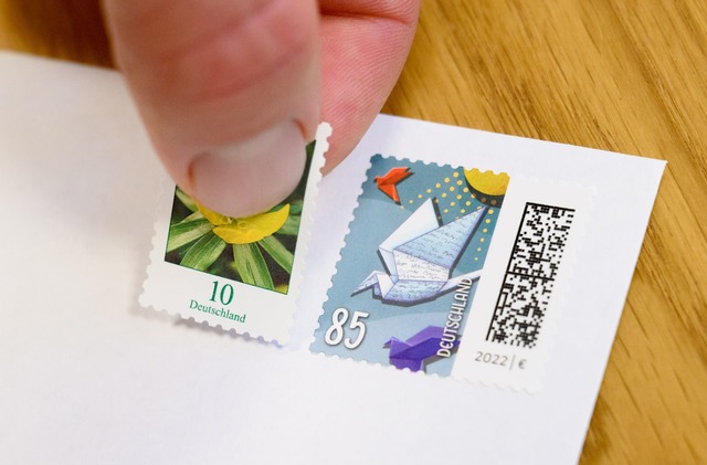 Eine 10-Cent-Briefmarke wird neben ein...-Briefmarke geklebt (gestellte Szene).  | Foto: Julian Stratenschulte/dpa