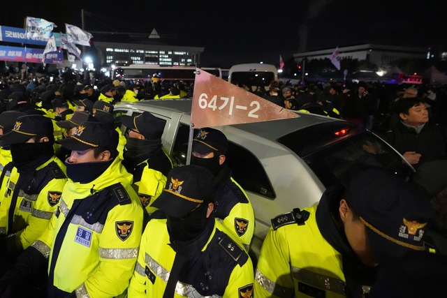 Polizisten vor dem Parlament sch&uuml;tzten Milit&auml;rfahrzeuge.  | Foto: Lee Jin-man/AP/dpa