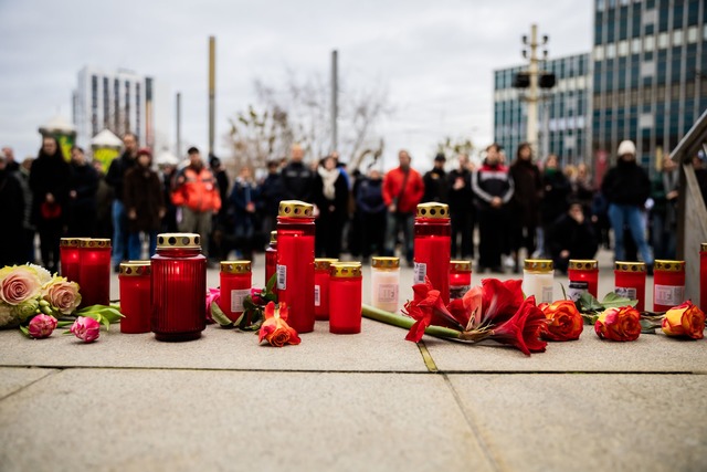 Menschen z&uuml;nden Kerzen an und legen Blumen nieder.  | Foto: Christoph Soeder/dpa