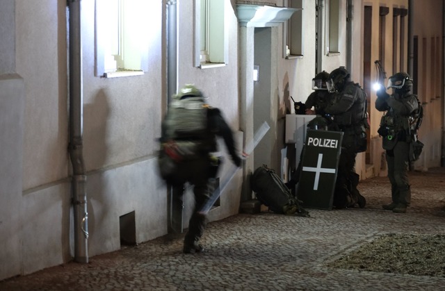 Am fr&uuml;hen Morgen durchsucht die P... auf dem Weihnachtsmarkt ein Wohnhaus.  | Foto: Sebastian Willnow/dpa