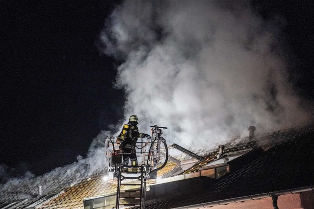 Ein Feuerwehrmann l&ouml;scht den Brand in einem Mehrfamilienhaus.  | Foto: Kohls/SDMG/dpa