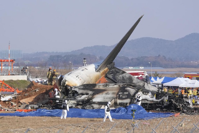 Feuerwehrleute und Mitglieder eines Re...ugzeugs am Muan International Airport.  | Foto: Ahn Young-joon (dpa)