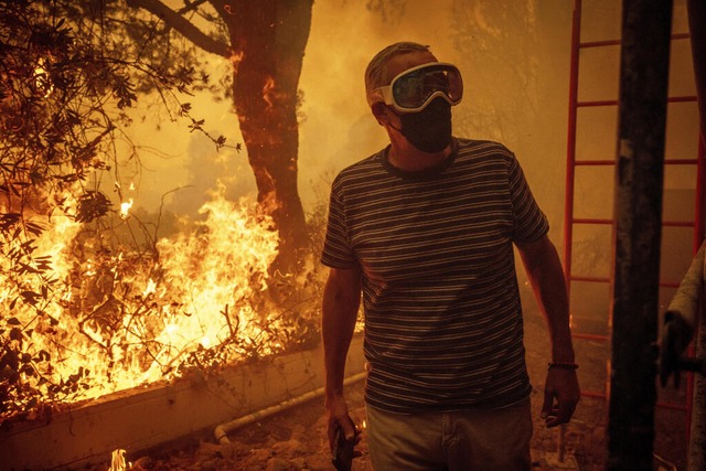 Ein Anwohner beobachtet, wie sich die ...n des Feuers seinem Grundstck nhern.  | Foto: Ethan Swope (dpa)