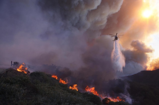 Ein Hubschrauber wirft Wasser auf das ...eil Pacific Palisades von Los Angeles.  | Foto: Etienne Laurent (dpa)