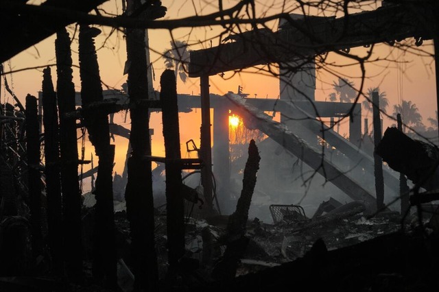 Die Sonne geht auf, nachdem das Feuer ...tteil Pacific Palisades verwstet hat.  | Foto: Damian Dovarganes (dpa)