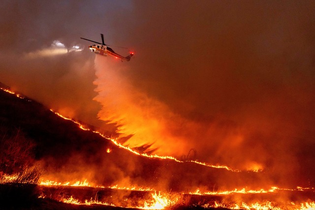 Flug durch das Inferno: Ein Hubschraub...uer in den West Hills von Los Angeles.  | Foto: Ethan Swope/AP/dpa