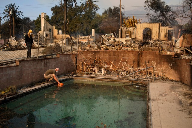 Robert Karban f&uuml;llt einen Eimer mit Wasser aus einem Swimmingpool.  | Foto: John Locher/AP/dpa