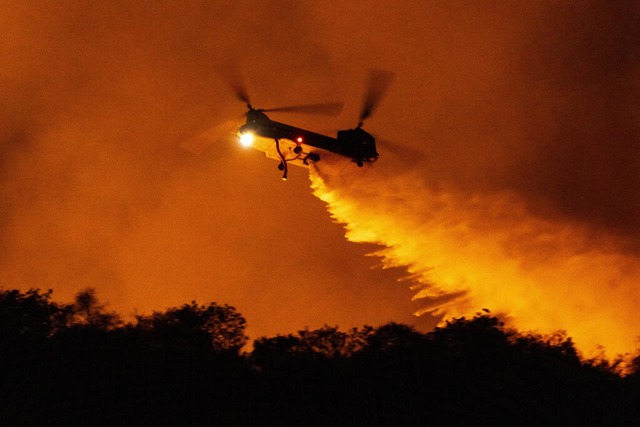 Ein Hubschrauber wirft Wasser auf das Palisades-Feuer im Mandeville Canyon ab.  | Foto: Etienne Laurent (dpa)