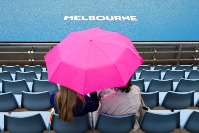 Zuschauerinnen sitzen w&auml;hrend ein...inem Regenschirm auf der Trib&uuml;ne.  | Foto: Frank Molter/dpa