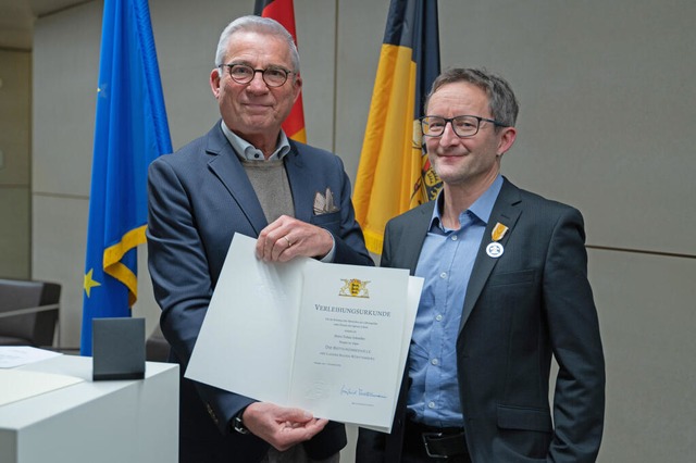 Der Lehrer Tobias Schneller (rechts) e...bel eine Rettungsmedaille und Urkunde.  | Foto: Helena Dolderer (dpa) 