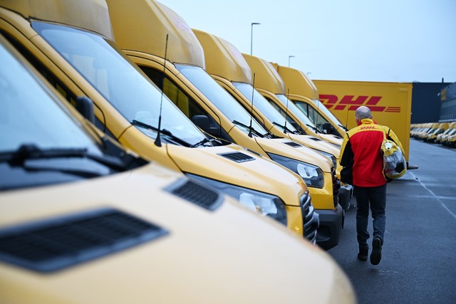 Auch er f&auml;hrt Stromer: ein DHL-Pa...dem Weg zu seinem Elektro-Transporter.  | Foto: Wolf von Dewitz/dpa