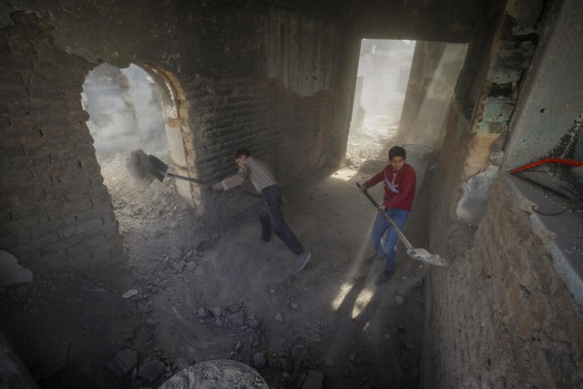 Zwei Jungen schaufeln Schutt, whrend ...ie in Damaskus, Syrien, zu reparieren.  | Foto: Omar Sanadiki (dpa) 